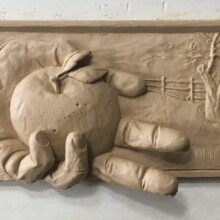 This is a clay state of of a memorial plaque for THOMAS NELSON BURFORD at the Old City Cemetery in Lynchburg, VA. The memorial depicts a hand holding an apple and reaching out of the frame.