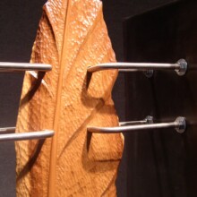 Detail photograph of woodcarved feather titled "COMPROMISED VII." Made with wood, stainless steel, and steel.